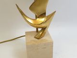 une lampe dorée posée sur un socle en bois