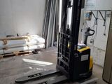 a forklift in the middle of a room with a lot of pallets