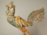 statue représentant un oiseau posée sur un socle en bois, sur fond blanc