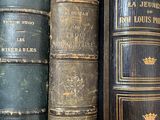several old books are lined up on a shelf in a library