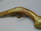 a close up of a brass plated gun on a white surface