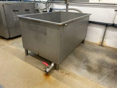 un grand récipient métallique muni d'une poignée, posé par terre