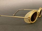 gold sunglasses with brown lenses on a black surface