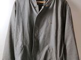 a grey jacket hanging on a hanger against a white wall