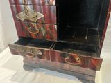 a small chest of drawers that has a painting on it