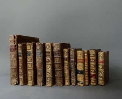 several old books are lined up in a row on a gray surface
