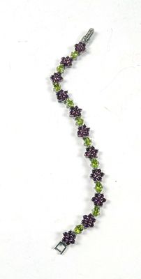 Collier de perles violettes et vertes sur fond blanc, avec un fermoir en argent