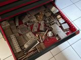 une boîte à outils rouge contenant des outils, posée sur un sol carrelé