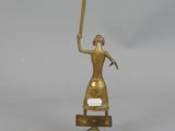 brass statue of a woman holding a baseball bat on a stand