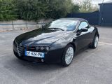 La voiture noire est garée sur le parking, à côté d'une clôture.