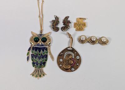 several pieces of jewelry including an owl, a necklace, and a key