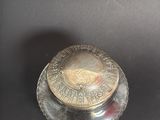 a silver plate with a metal lid on a black surface