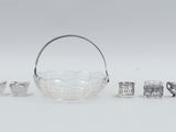 an assortment of silver and glass objects including a basket, spoon, and other items