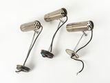 three metal lights on a white surface with wires attached to them