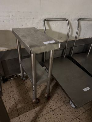 trois tables en acier inoxydable dans une pièce au sol carrelé