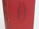 un vieux livre rouge posé sur une table blanche
