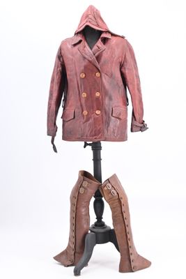 un manteau en cuir et des bottes posés sur un présentoir, sur fond blanc
