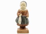 figurine représentant une femme tenant un sac, posée sur un socle en bois