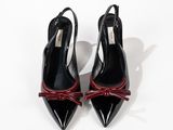 a pair of black and red shoes with bows on the toes