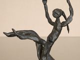 statue of a woman sitting on a tree branch with her arms in the air