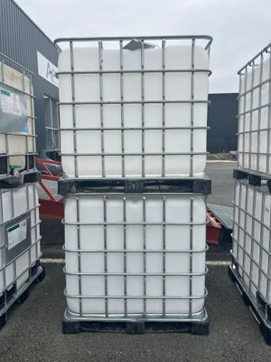 deux grands conteneurs remplis d'eau posés sur des palettes dans un parking