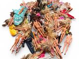 a pile of barbie dolls on a white surface