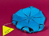 a blue origami flower on a red surface with a yellow tag
