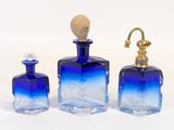trois bouteilles en verre bleu et un robinet doré posés sur un plan de travail blanc
