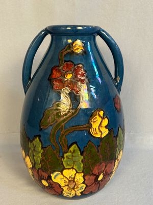 un vase bleu sur lequel sont peints un oiseau et des fleurs