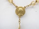 gold plated necklace with a coin and glass beads on a mannequin