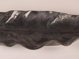 a black leaf shaped object on a white wall