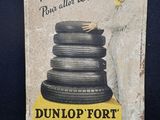 une vieille enseigne en tôle faisant la promotion des pneus Dunlop sur fond bleu