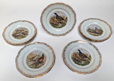 four plates with birds painted on them sitting on a white surface