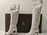 Les bottes sont blanches et ont des boutons dorés au talon.