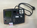 une image représentant une calculatrice posée sur une table, à côté d'un chargeur
