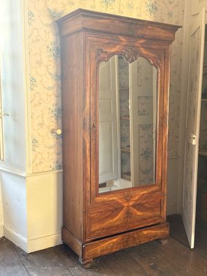 a wooden cabinet with a glass door in the corner of a room