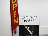 a sign that says vape shop over it next to an open sign