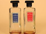 two bottles of perfume sitting next to each other on a table