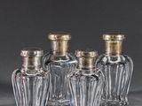 cinq petites bouteilles en verre avec des bouchons argentés posées sur une table