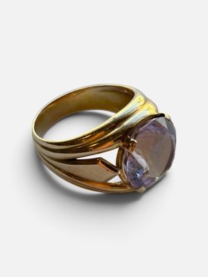gros plan d'une bague en or avec une pierre violette