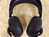 two black headphones sitting on top of a bamboo tray