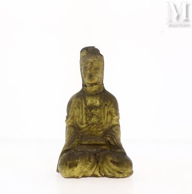 une statue en or représentant une personne assise sur une surface blanche