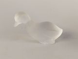 a small glass duck that is sitting on a table
