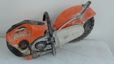 an orange and black chainsaw sitting on top of a white surface