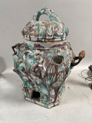 une théière en céramique avec son couvercle, posée sur une table à côté d'une lampe