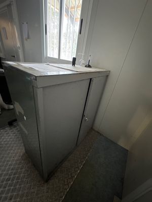 un petit réfrigérateur dans un coin de la pièce, près d'une fenêtre