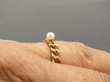 someone is holding a gold ring with a pearl on it