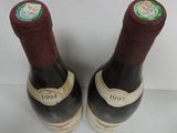 pair of two bottles of wine with labels on them sitting on a table