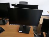 trois écrans d'ordinateur posés sur un bureau dans un bureau