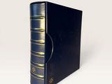an old black book sitting on top of a white table